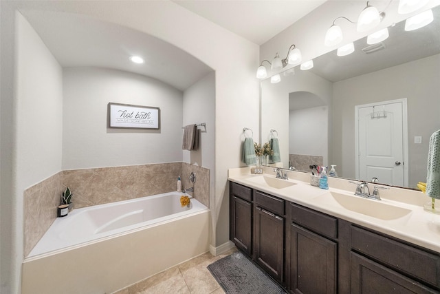full bathroom with double vanity, tile patterned floors, a sink, and a bath