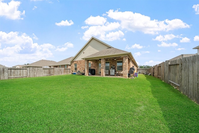 rear view of property featuring a fenced backyard, a patio, a lawn, and brick siding