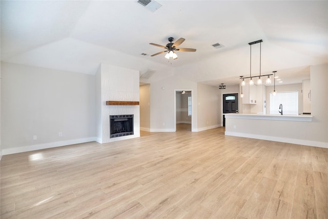 unfurnished living room featuring visible vents, a ceiling fan, vaulted ceiling, and a fireplace