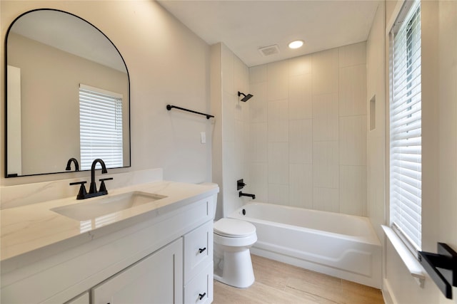 full bathroom with visible vents, wood finished floors, vanity, toilet, and washtub / shower combination