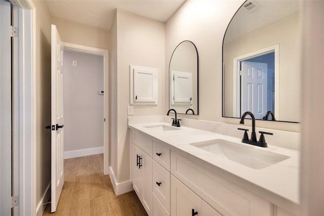 full bathroom with visible vents, a sink, baseboards, and wood finished floors