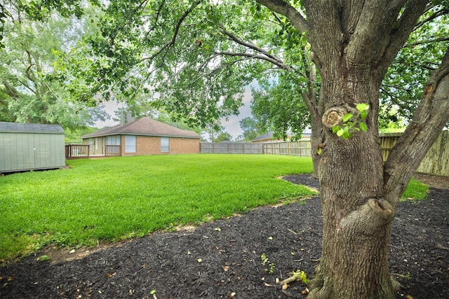view of yard with a fenced backyard, a shed, and an outbuilding