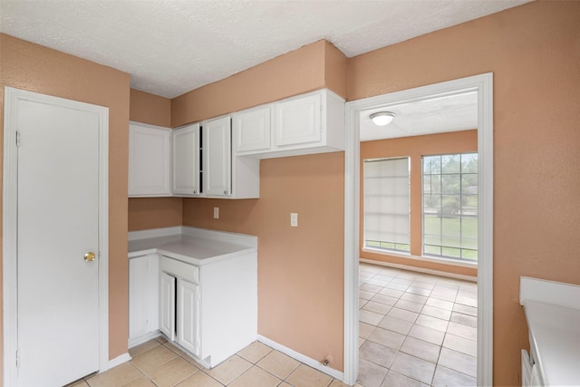 4027 Brookhead Trl, Houston, TX 77066 - kitchen with white cabinets, light tile patterned flooring, light countertops, a textured ceiling, and baseboards