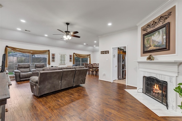 living room with a premium fireplace, a ceiling fan, wood finished floors, visible vents, and ornamental molding