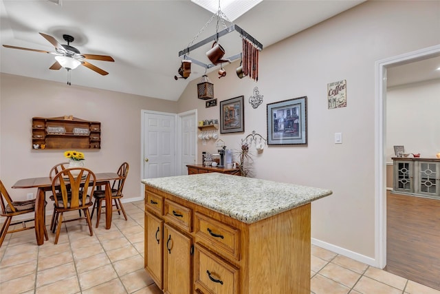 kitchen featuring a ceiling fan, baseboards, light tile patterned floors, lofted ceiling, and a kitchen island