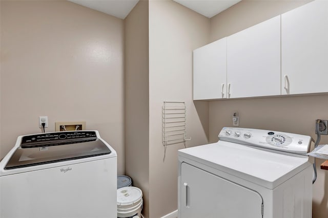 clothes washing area featuring cabinet space, baseboards, and washing machine and dryer