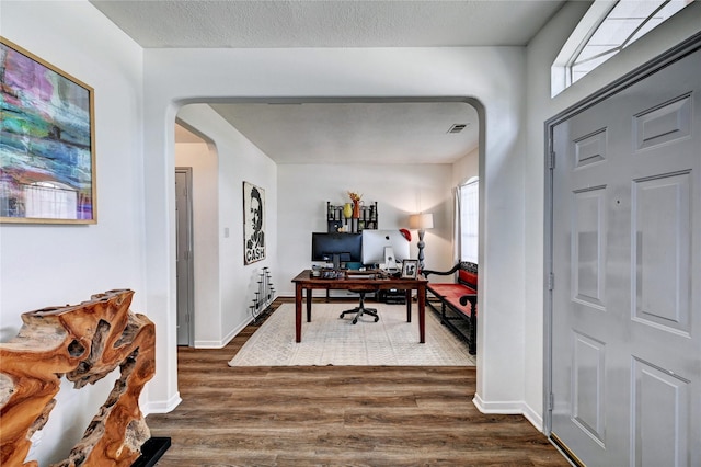office with visible vents, arched walkways, dark wood-style floors, and a healthy amount of sunlight