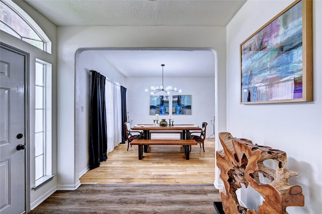 foyer entrance featuring a textured ceiling, an inviting chandelier, and wood finished floors