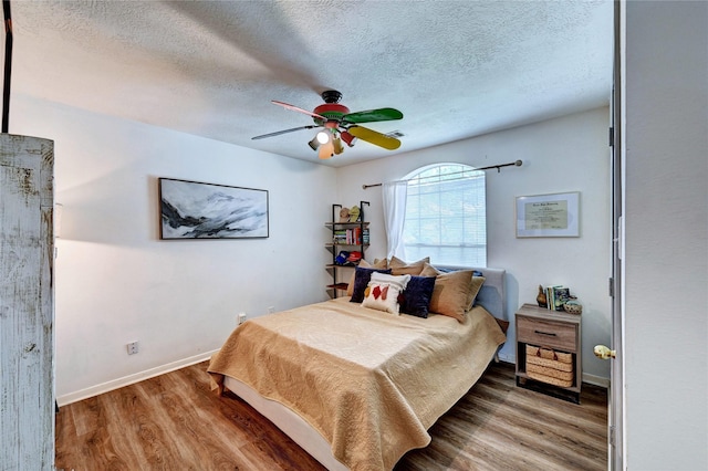 bedroom featuring baseboards, ceiling fan, a textured ceiling, and wood finished floors
