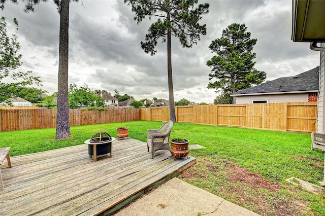 view of yard with a fire pit, a fenced backyard, and a wooden deck