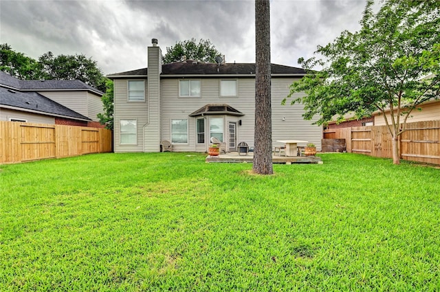 rear view of property with a lawn, a fenced backyard, a patio area, and a chimney