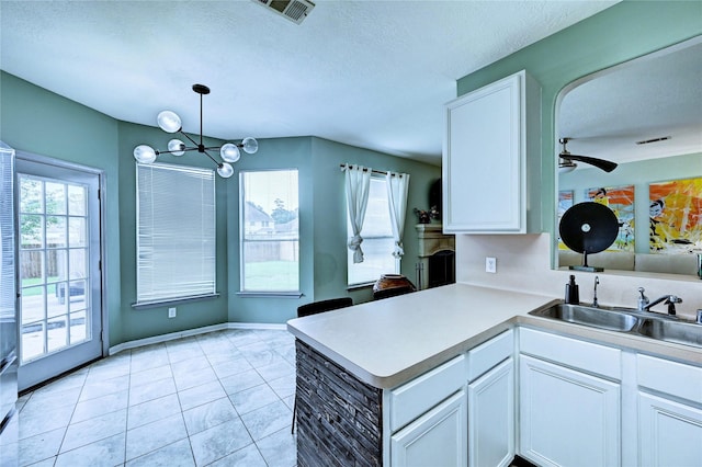 kitchen featuring a sink, light tile patterned floors, white cabinetry, and visible vents