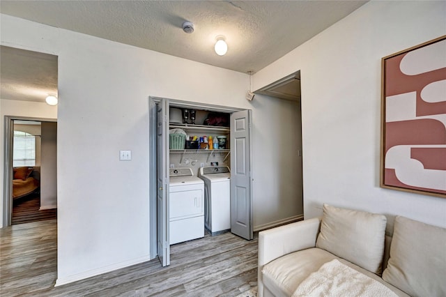 washroom with laundry area, light wood finished floors, a textured ceiling, and washer and dryer
