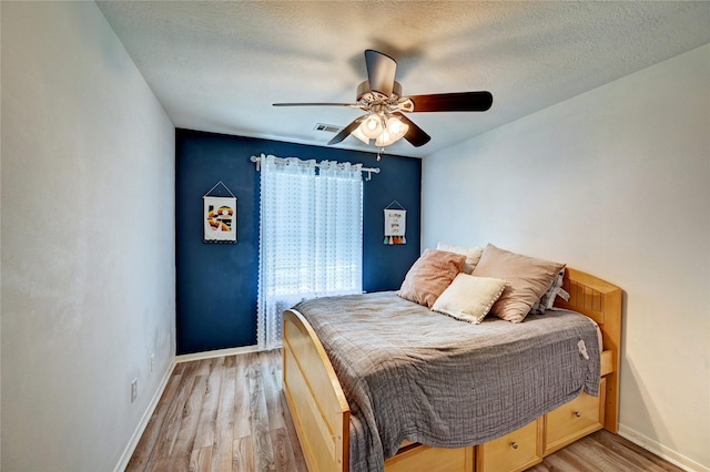 bedroom with light wood-style floors, baseboards, ceiling fan, and visible vents