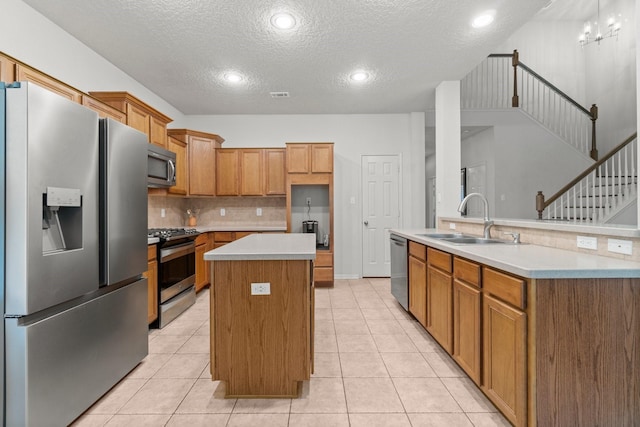 kitchen with a sink, a textured ceiling, stainless steel appliances, tasteful backsplash, and a kitchen island