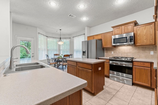 kitchen featuring a healthy amount of sunlight, visible vents, appliances with stainless steel finishes, a center island, and a sink