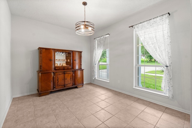 spare room with light tile patterned flooring, a chandelier, and a healthy amount of sunlight