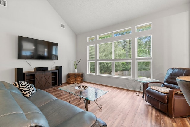 living room featuring high vaulted ceiling, visible vents, and wood finished floors