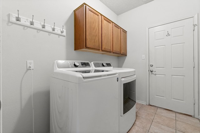 clothes washing area featuring cabinet space, light tile patterned floors, and washer and dryer