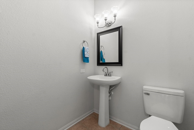bathroom featuring baseboards, tile patterned floors, and toilet
