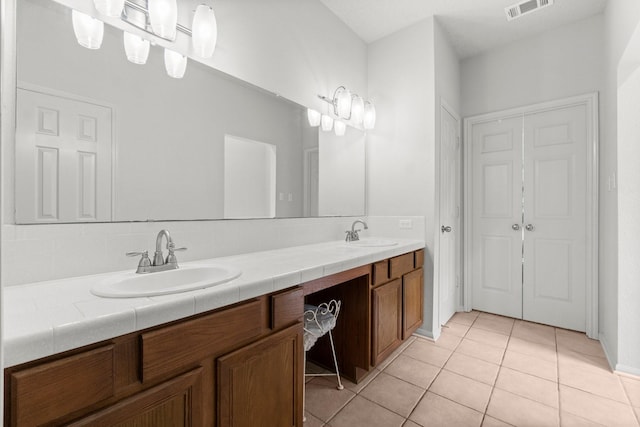 full bathroom featuring double vanity, tile patterned floors, visible vents, and a sink