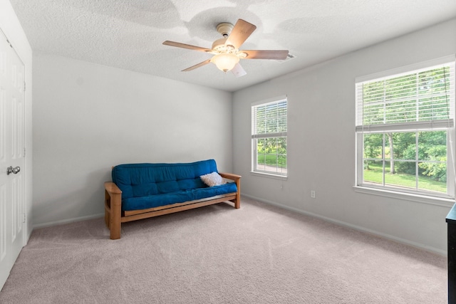 sitting room with a textured ceiling, ceiling fan, baseboards, and carpet
