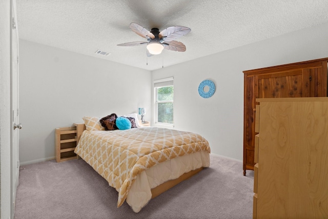 bedroom featuring visible vents, light carpet, baseboards, ceiling fan, and a textured ceiling