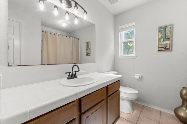 bathroom with vanity, curtained shower, toilet, baseboards, and tile patterned floors