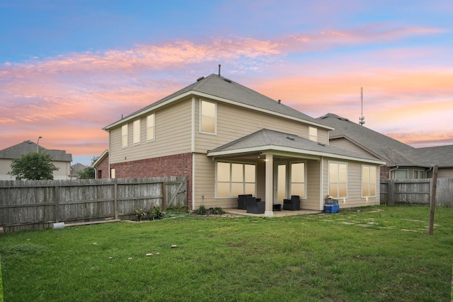 25404 Devonshire Knoll St, Katy, TX 77493 - back of property at dusk featuring a yard, a patio, brick siding, and a fenced backyard