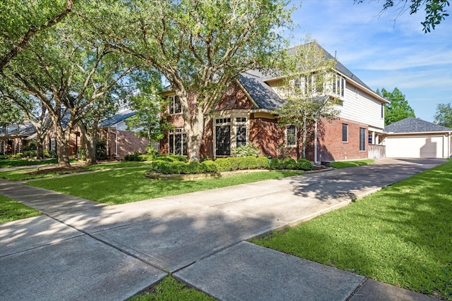 view of front of home with a garage, an outdoor structure, a front yard, and brick siding