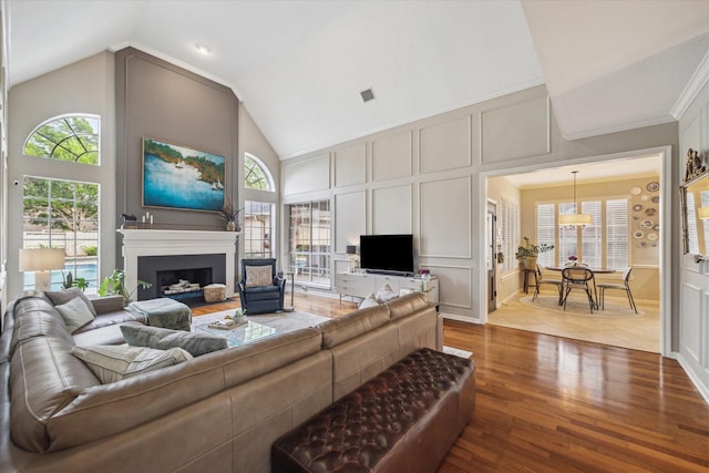 living room featuring a fireplace, plenty of natural light, wood finished floors, and a decorative wall