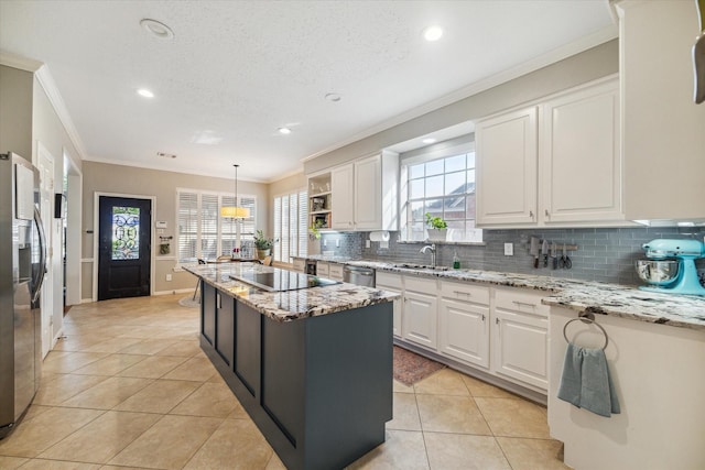 kitchen featuring tasteful backsplash, ornamental molding, stainless steel appliances, white cabinetry, and an island with sink