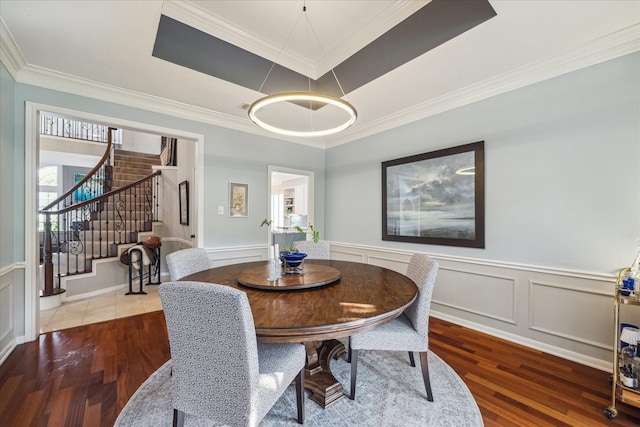 dining room featuring stairway, crown molding, a tray ceiling, and wood finished floors