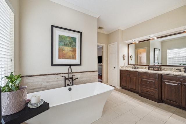full bath featuring a sink, tile patterned flooring, a freestanding tub, visible vents, and ornamental molding