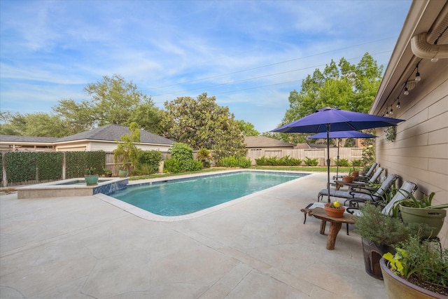 view of swimming pool featuring a patio, a pool with connected hot tub, and a fenced backyard