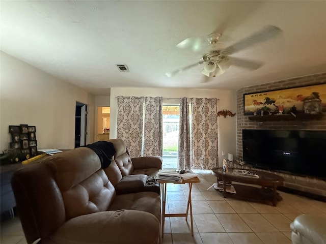 tiled living room featuring visible vents, a brick fireplace, and ceiling fan