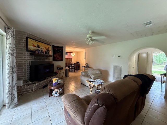 living room featuring visible vents, a brick fireplace, and light tile patterned flooring