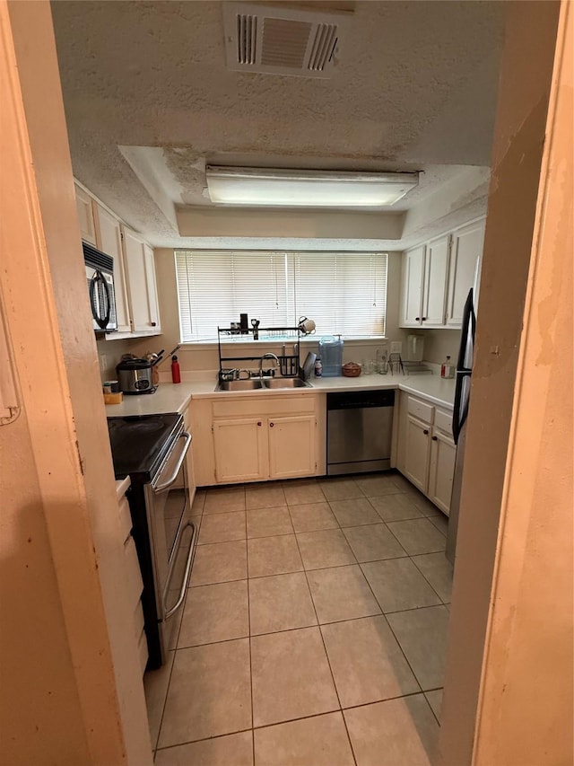 kitchen featuring stainless steel appliances, a textured ceiling, visible vents, and a sink