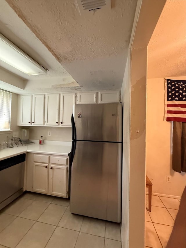 kitchen with freestanding refrigerator, white cabinets, light tile patterned floors, and dishwasher