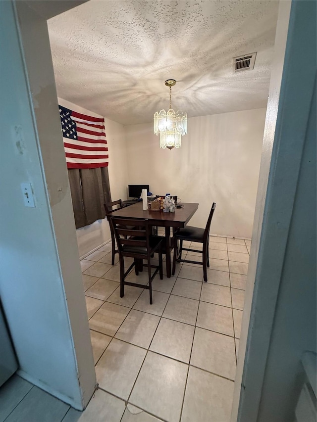 dining room featuring an inviting chandelier, a textured ceiling, light tile patterned flooring, and visible vents