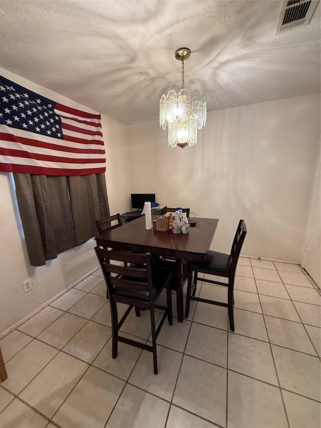 dining space featuring a textured ceiling, a notable chandelier, visible vents, and light tile patterned floors