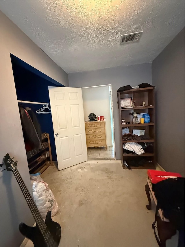 interior space with a textured ceiling, visible vents, and concrete floors