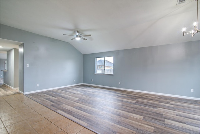 empty room featuring visible vents, vaulted ceiling, wood finished floors, baseboards, and ceiling fan with notable chandelier