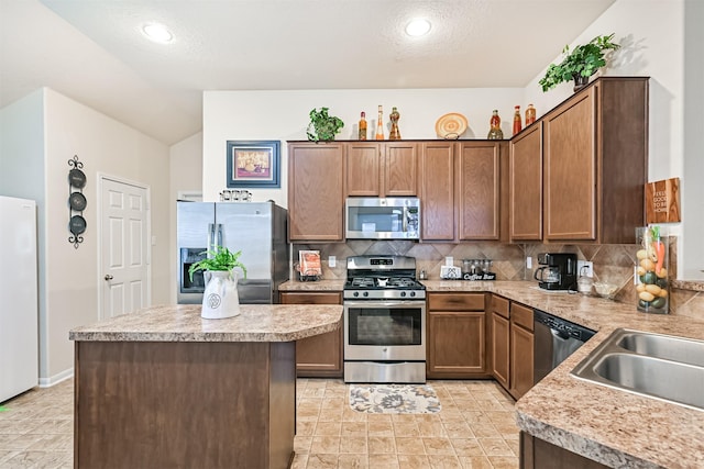 kitchen with a sink, light countertops, a center island, stainless steel appliances, and tasteful backsplash