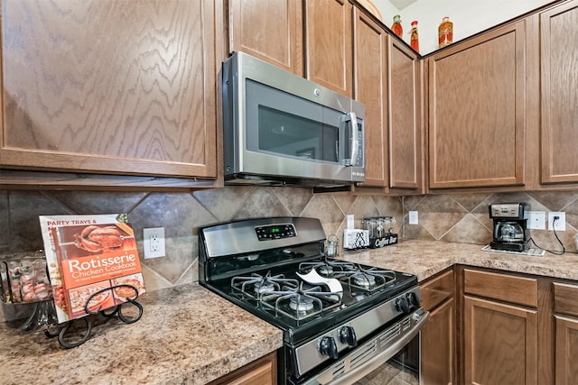 kitchen featuring light countertops, backsplash, brown cabinets, and appliances with stainless steel finishes