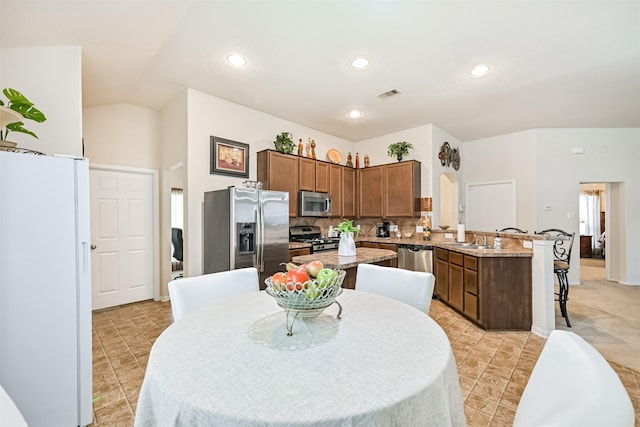 kitchen featuring visible vents, a peninsula, tasteful backsplash, a sink, and appliances with stainless steel finishes
