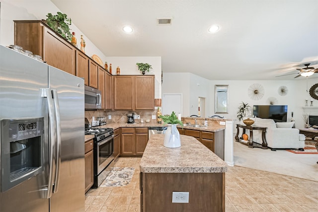 kitchen with visible vents, a peninsula, open floor plan, light countertops, and stainless steel appliances