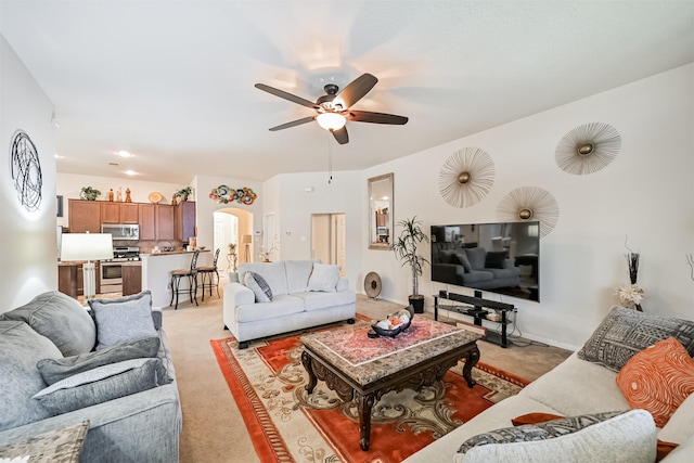 living room with arched walkways, ceiling fan, and light colored carpet