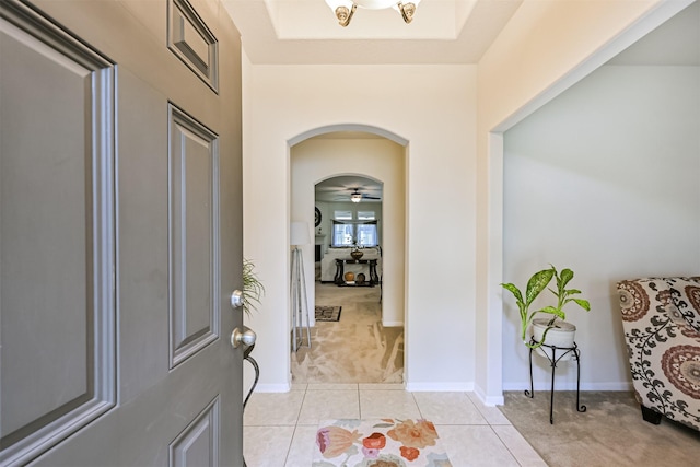 foyer featuring arched walkways, light tile patterned floors, and light carpet
