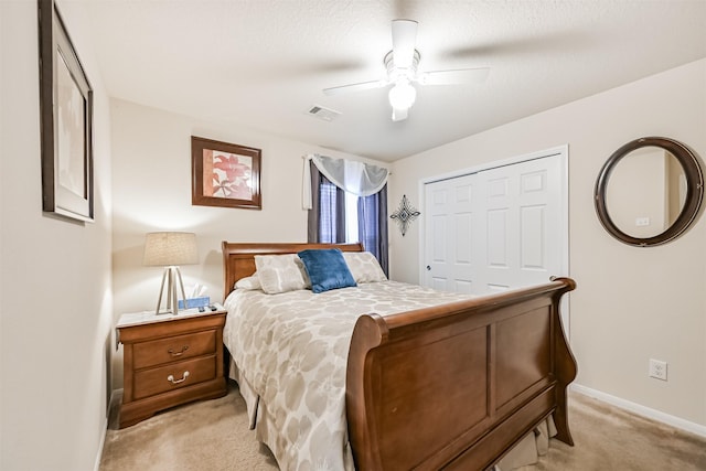 bedroom featuring visible vents, a closet, baseboards, ceiling fan, and light colored carpet